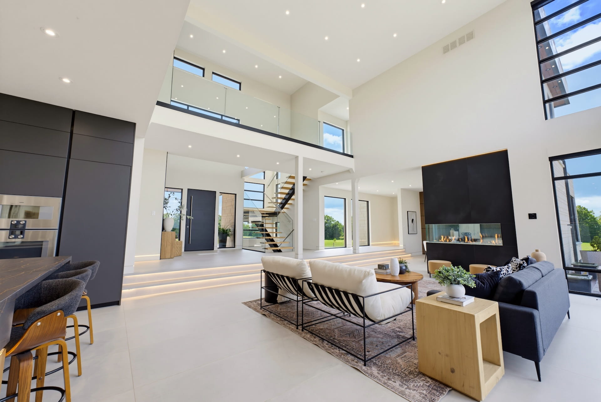 Double-height great room with a window wall, open oak stair and linear fireplace