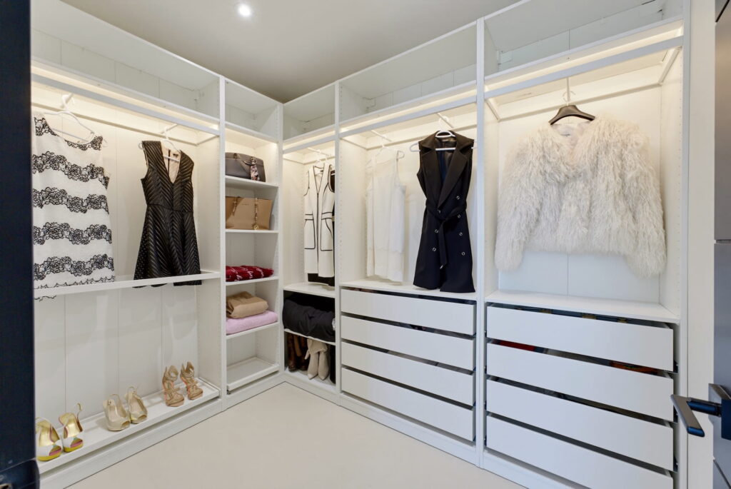 Walk-in dressing room with lit open shelving and built-in drawers