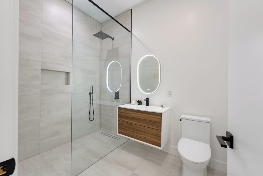 Ensuite bathroom with a glass walk-in shower, floating oak vanity and backlit mirrors