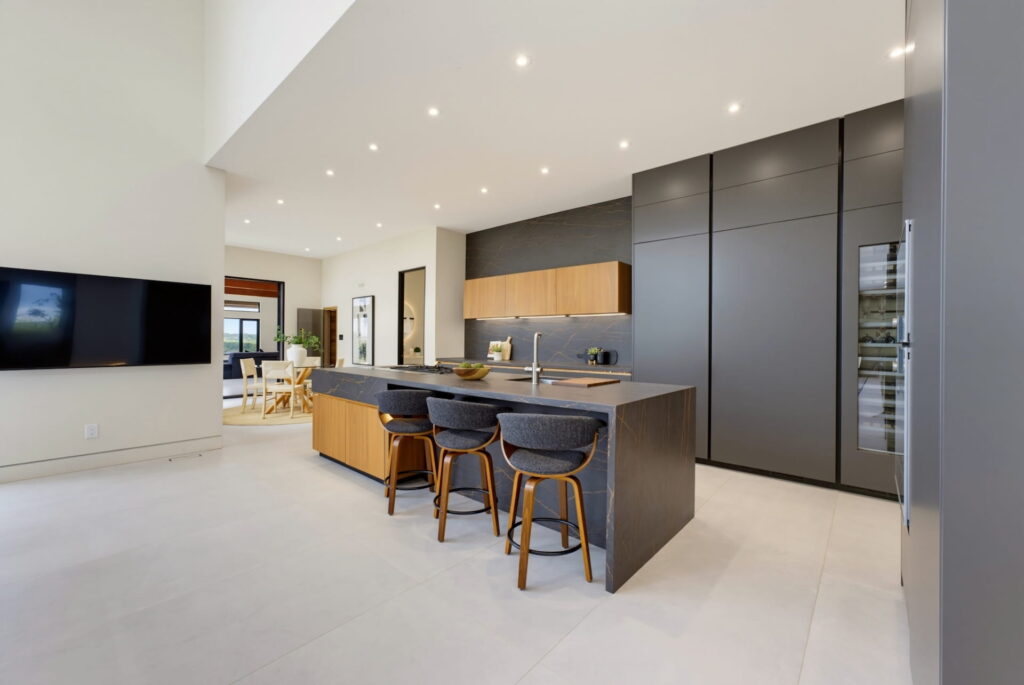 Contemporary kitchen with dark full-height cabinetry and a waterfall island with bar stools