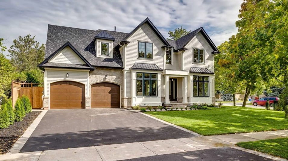 Stone-and-stucco two-storey family home with a double garage on a tree-lined street