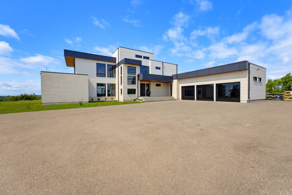 Front elevation of a modern estate with a stone-and-glass facade and a triple garage